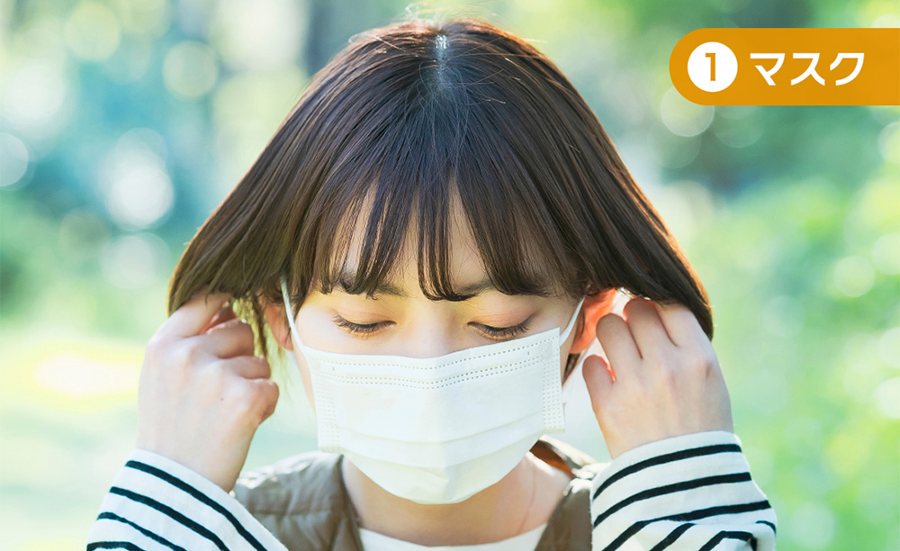 マスクを着用し、髪を耳にかける女性の横顔。花粉対策の外出イメージ。